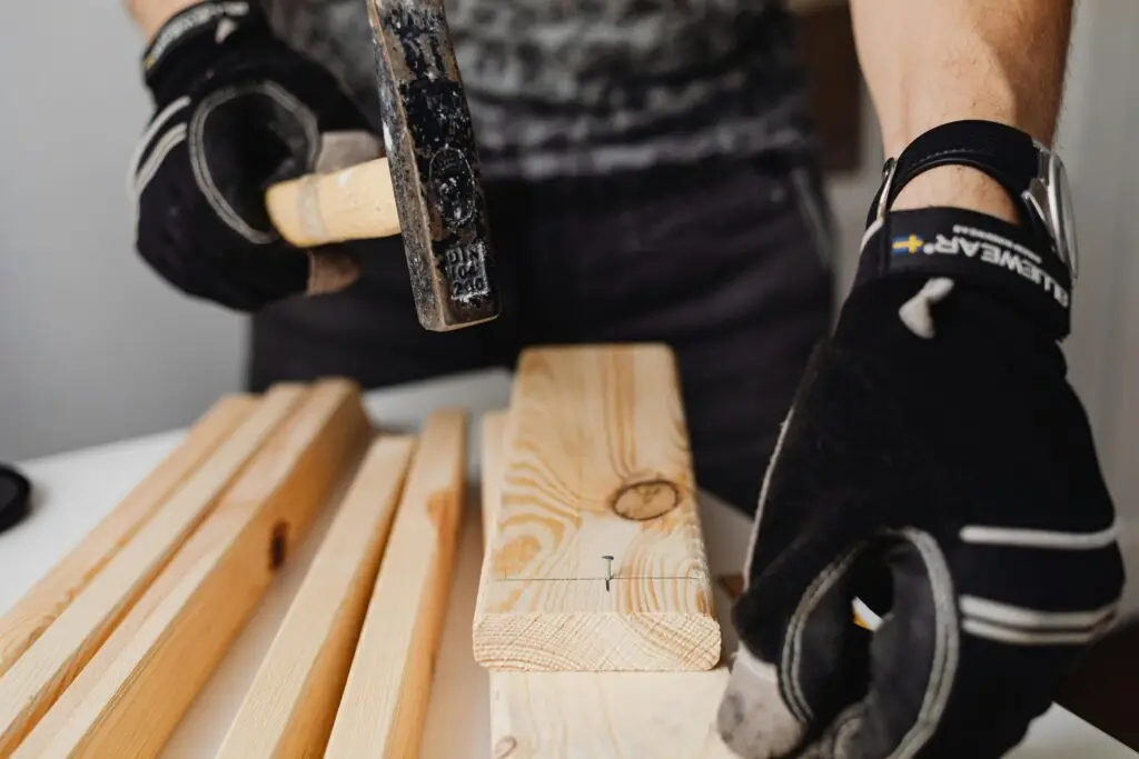 Handyman hammering a nail into a wooden plank.