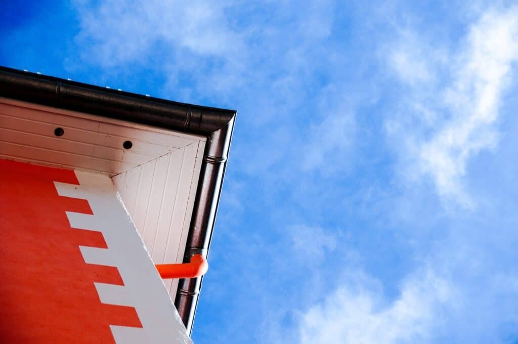 Corner of a building with a zigzag pattern against a blue sky with shiny rain gutters.