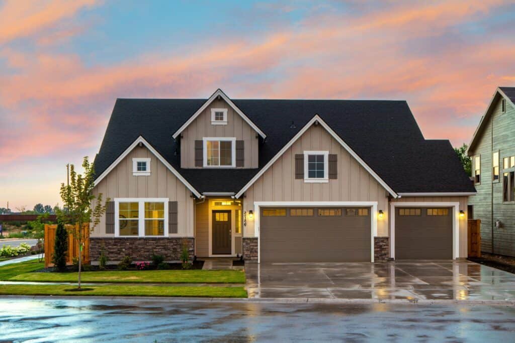 A two-story suburban house with a double garage under a colorful sunset sky.