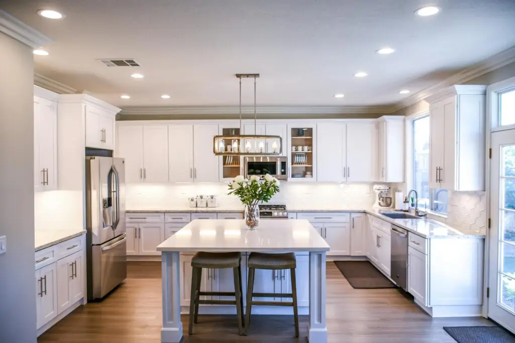 Modern kitchen with white cabinets, stainless steel appliances, and an island with bar stools.
